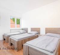 Three beds in a room with a wooden floor and a painting on the wall.