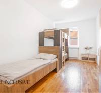 The interior of a bedroom in a building with beds and a wooden decor floor.
