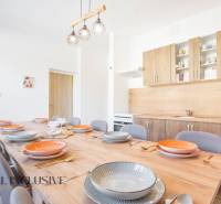A kitchen in a building, wooden cabinets, a large table with a wooden decor floor.