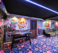 The interior of a building with graffiti on the walls, colorful carpets, and a table hockey game.