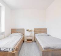 A room with two beds, a nightstand, and a floor with a wooden decor.