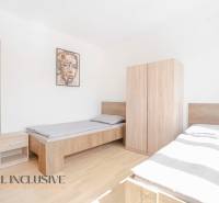 A bedroom with two beds and furniture, a floor with a wooden decor, a picture on the wall.