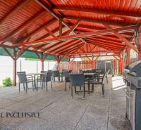 An exterior terrace of a building in Dunajská Streda with a wooden roof and a grill.