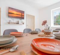 A dining room in a building with a decorative table, colorful plates, and a television on the wall.