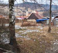 Snow-covered gardens in Nálepkovo with cottages and a view of the hills and church.