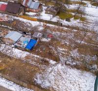 A winter garden in Nálepkovo with snow-covered cottages and trees, contrasting with the brown soil.