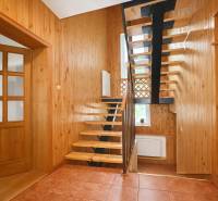 A hallway in a family house with wooden paneling, a staircase, and ceramic tiles.