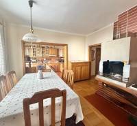 Dining room in a family house with a fireplace and kitchen, floor with wooden decor.