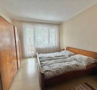 Bedroom with a double bed, wardrobe, and wooden decor flooring in a family house.