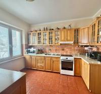 A kitchen with a corner wooden unit and appliances in a family house.