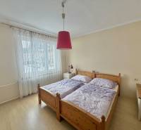 Bedroom with a double bed and a chandelier in a family house with a wood-patterned floor.