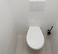 White toilet with a toilet paper holder and brush in the offices.