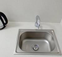 A kitchen sink with a kettle on a white countertop in an office.