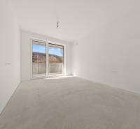 A spacious room with a gray floor and a large window in a 4-room apartment.