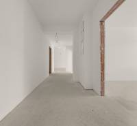 A hallway in a 4-room apartment with white walls and a concrete floor.