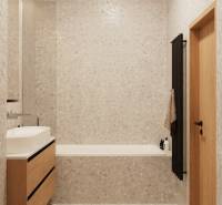 A bathroom with light tiles, a wooden cabinet under the sink, and a dark ladder radiator.