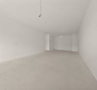 A spacious room in a 4-room apartment with white walls and an unfinished floor.