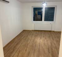 A room in a 3-room apartment with a window, a light fixture, and a floor with a wooden decor.