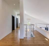 Interior of a villa with white walls, a floor with a wood decor, and a railing.
