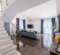 Living room of the villa with a shiny floor and blue curtains.