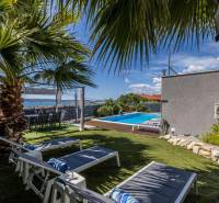 A cozy garden with a pool in a villa in Kaštela, surrounded by palm trees and loungers.