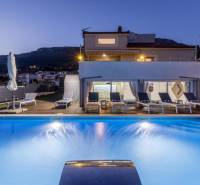 Night Villa in Kaštela with a pool, sun loungers, and a view of the mountains in the background.