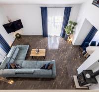 A villa with a view of the living room with a blue sofa and marble floor.
