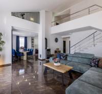 Living room of a villa with a comfortable sofa, dining area, and staircase, floor with wooden decor.