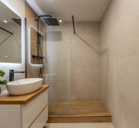 A bathroom in a 2-room apartment with a sink and a shower, floor with wood decor.