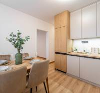 Dining table with chairs and a kitchen unit with a wooden decor floor in a 2-room apartment.
