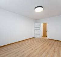 A room in a 2-room apartment with a wooden decor floor and white walls.