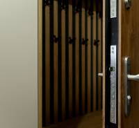 A view of open entrance doors and a coat rack wall with a wooden decor floor.