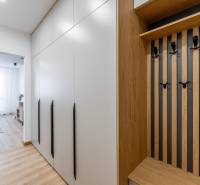 An entrance hall with a wooden-patterned floor, a large wardrobe, and a coat rack in a 2-room apartment.