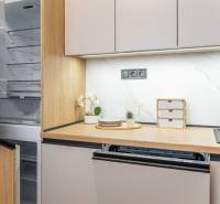 A kitchen unit in a 2-room apartment with an open refrigerator and a wooden decor floor.