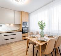 A kitchen in a 2-room apartment with a wooden decor floor and a dining table.