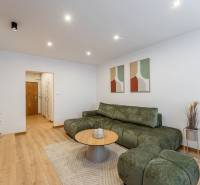 Living room in a two-room apartment with a wooden decor floor, green sofa, coffee table.