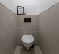 A stylish toilet with a minimalist design in a 2-room apartment, tiled with elegant gray tiles.