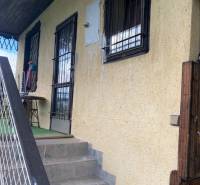 Entrance stairs and window grilles of the cottage in Vyšné Opátske, Košice, with a yellow facade.
