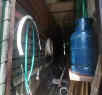 Storage space at the cottage with hoses, a gas tank, and various tools in Košice.
