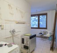 A kitchen in a 2-room apartment with old furnishings and a floor with a wooden decor.