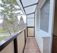 Balcony in a 2-room apartment with a view of greenery, tiled floor.