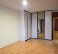 A room with a wooden decor floor, a built-in wardrobe, and doors in a 2-room apartment.
