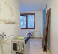 Unfurnished kitchen in a 2-room apartment with light floor tiles and a window.