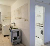 Incomplete kitchen and laundry room in a 2-bedroom apartment with ceramic tiles.