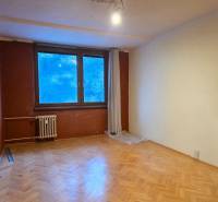 A room with a wooden decor floor and a large window in a two-room apartment.