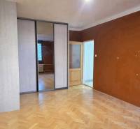 A room in a 2-room apartment with a wood-decor floor and wardrobes with sliding doors.
