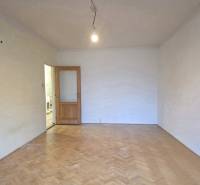 A room in a 2-room apartment with a wooden decor floor and open doors.