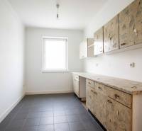 A kitchen in a family house with older cabinets and tiles on the floor.