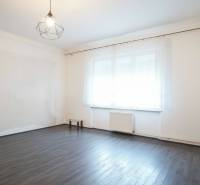 A room in a family house with a wood-patterned floor and a large window.