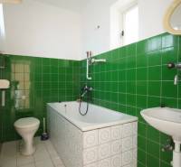 A bathroom in a family house with green tiles and a classic bathtub.